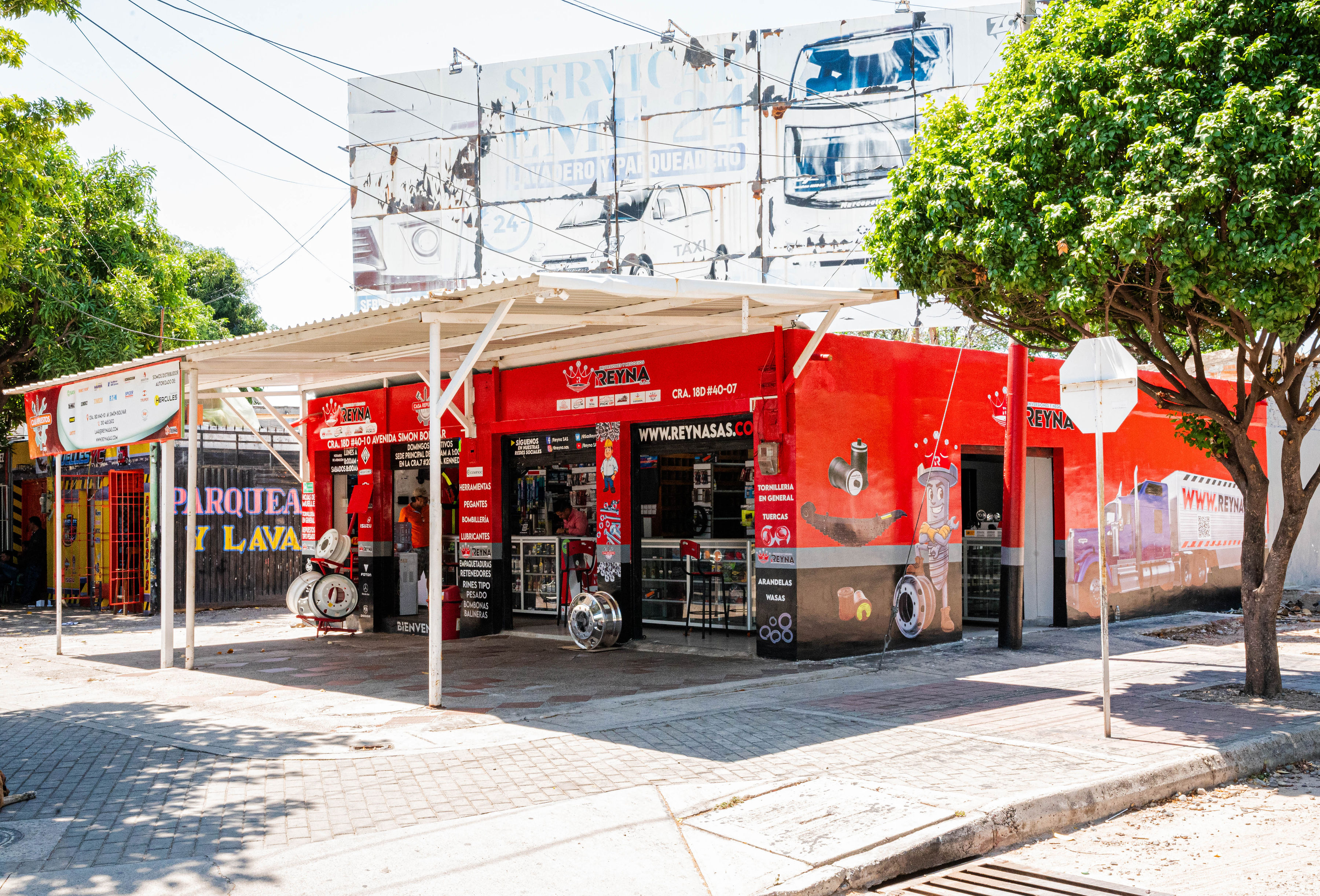 Fachada lateral de La Casa de La 40 en Valledupar con toldo rojo y exhibición de productos en la acera