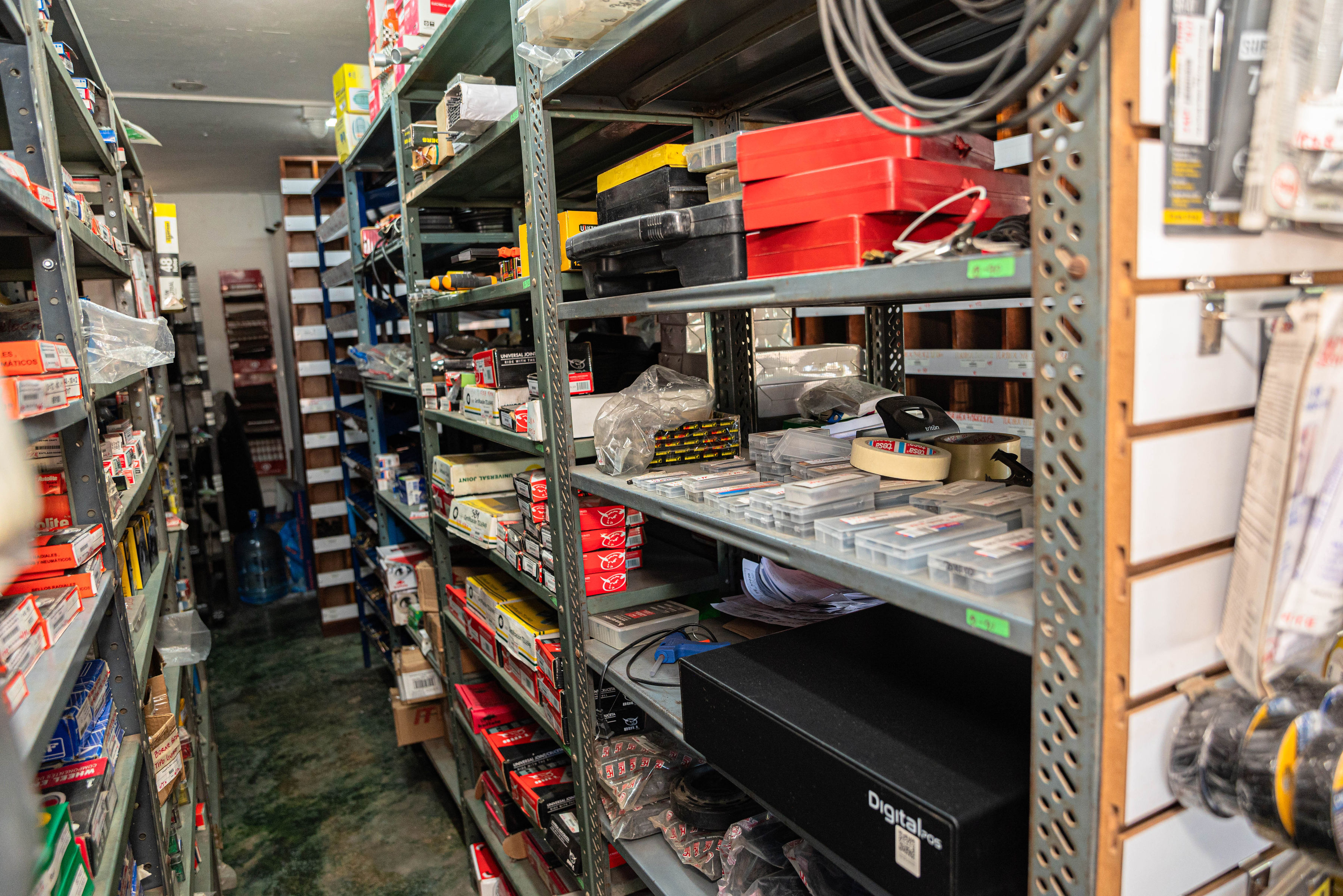 Estanterías de bodega con mangueras, correas y repuestos automotrices variados en La Casa de La 40